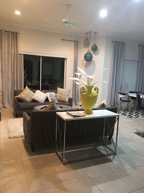 Relax in a stylish living room with a sofa, dining area, and ceiling fan.