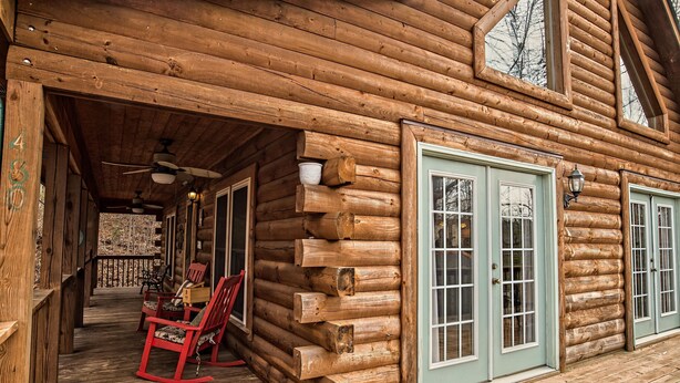 Eine Blockhütte mit Veranda, Schaukelstühlen und einem Esstisch.