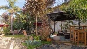 A garden patio with a stone pathway, outdoor furniture, and various plants. - Beautiful 1 Bedroom Apartment minutes to SFO in Victorian Home (Can sleep 4) (South San Francisco)