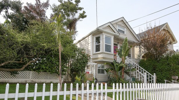 A two-story house with a white picket fence, a front porch, and a staircase leading to the second floor. - Beautiful 1 Bedroom Apartment minutes to SFO in Victorian Home (Can sleep 4) (South San Francisco)
