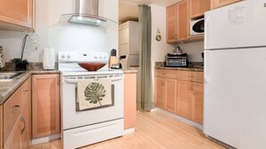A kitchen with wooden cabinets, a white stove, a microwave, and a refrigerator. - Beautiful 1 Bedroom Apartment minutes to SFO in Victorian Home (Can sleep 4) (South San Francisco)
