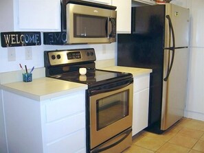 Kitchen features stainless steel appliances, white cabinetry, and a light-colored countertop.