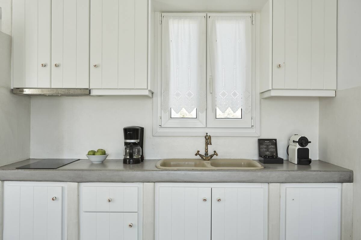 A kitchen with white cabinets, a double sink, a coffee maker, and a toaster.