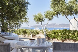 A white outdoor seating area with a table, two white mugs, and a bowl of cookies. - Iliana Olive Branch (Milos)