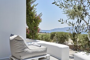 A white outdoor seating area with a view of the sea and mountains. - Iliana Olive Branch (Milos)