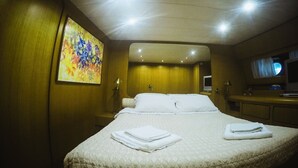 A hotel room with a large bed, a painting on the wall, a television, and a desk with a laptop. - Yacht Diva (Venice)