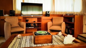 A living room with two armchairs, a coffee table with decorative items, a television, and a bookshelf. - Yacht Diva (Venice)