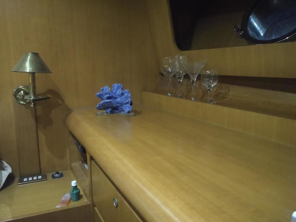 Une commode en bois avec un miroir, une lampe et une bouteille sur la table d’appoint.