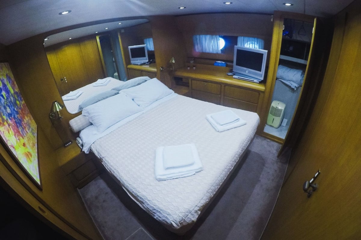 A hotel room with a large bed, two bedside tables, a TV on each side, and a small desk with a chair.