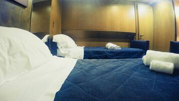 A hotel room with two beds, a wooden headboard, and a small table.