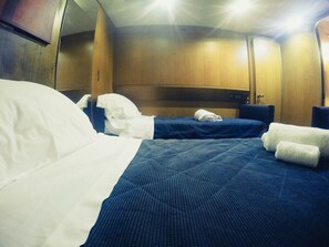 A hotel room with two beds, a wooden headboard, and a small table. - Yacht Diva (Venice)
