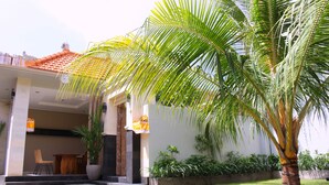 A house with a tiled roof, a covered porch, and a lawn. - Rusty Seminyak (Seminyak)