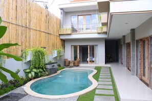 A modern house with a swimming pool, a balcony with plants, and a well-maintained garden.