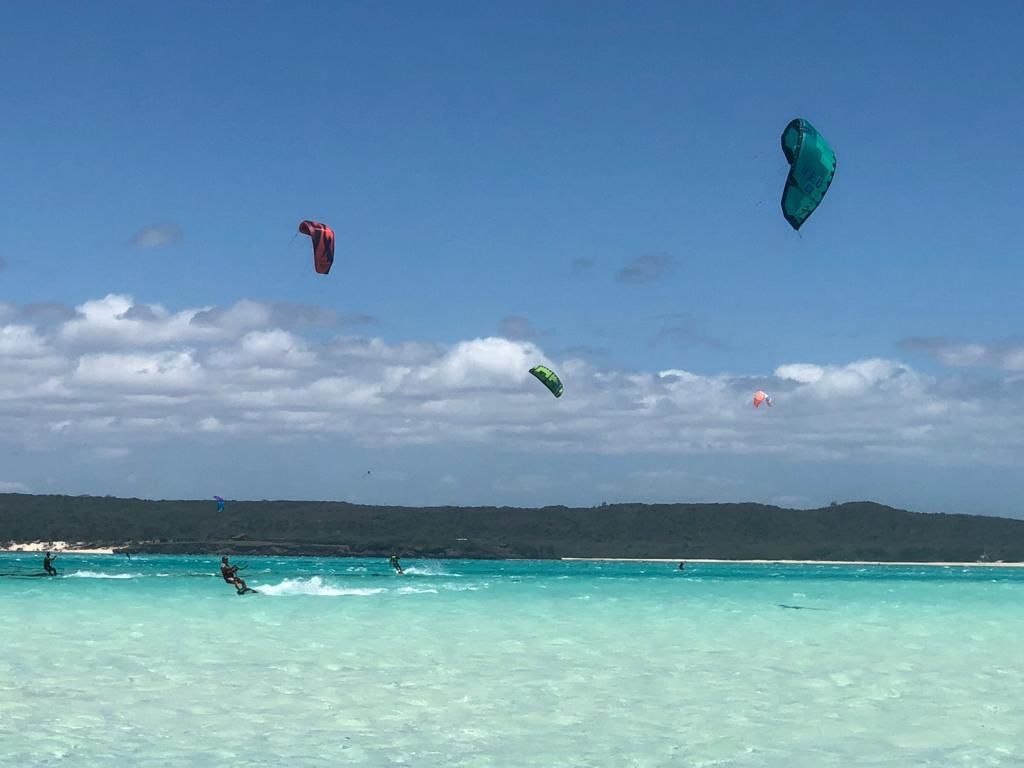 Una playa con aguas turquesas cristalinas y un paisaje montañoso en la distancia.