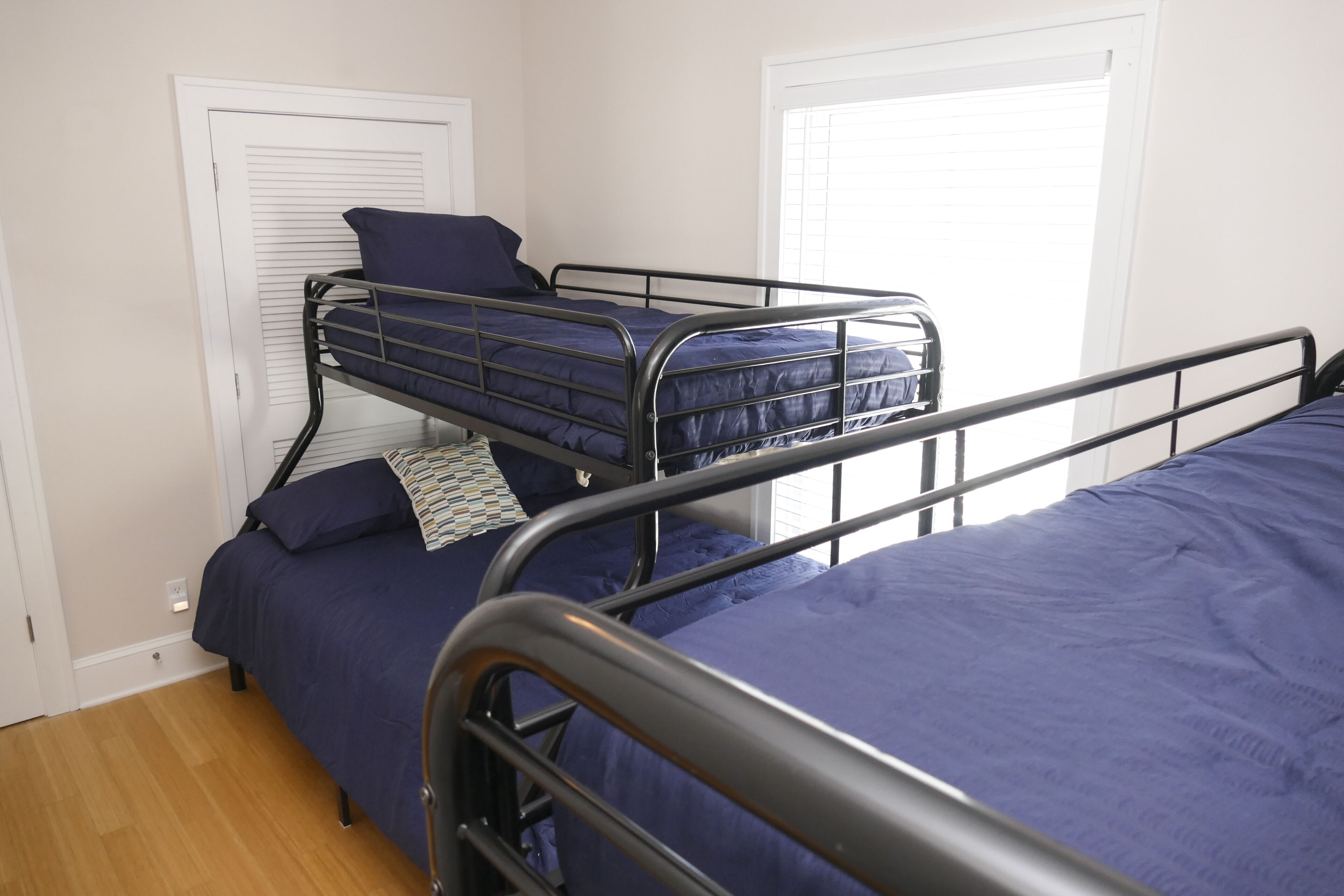 A dormitory room with two bunk beds, each with a blue mattress and matching pillows.