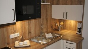 Una cocina moderna con armarios de madera, un lavamanos de acero inoxidable y un microondas negro.
