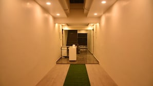 Un couloir étroit, doté d’une moquette verte, d’un plancher en bois et d’un comptoir d’accueil au bout.