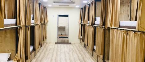 A corridor with bunk beds, wooden walls, and a tiled floor.