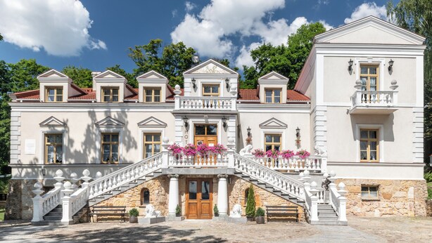Ein imposantes Gebäude mit einer zentralen Treppe, zahlreichen Fenstern und einem Steinfundament.
