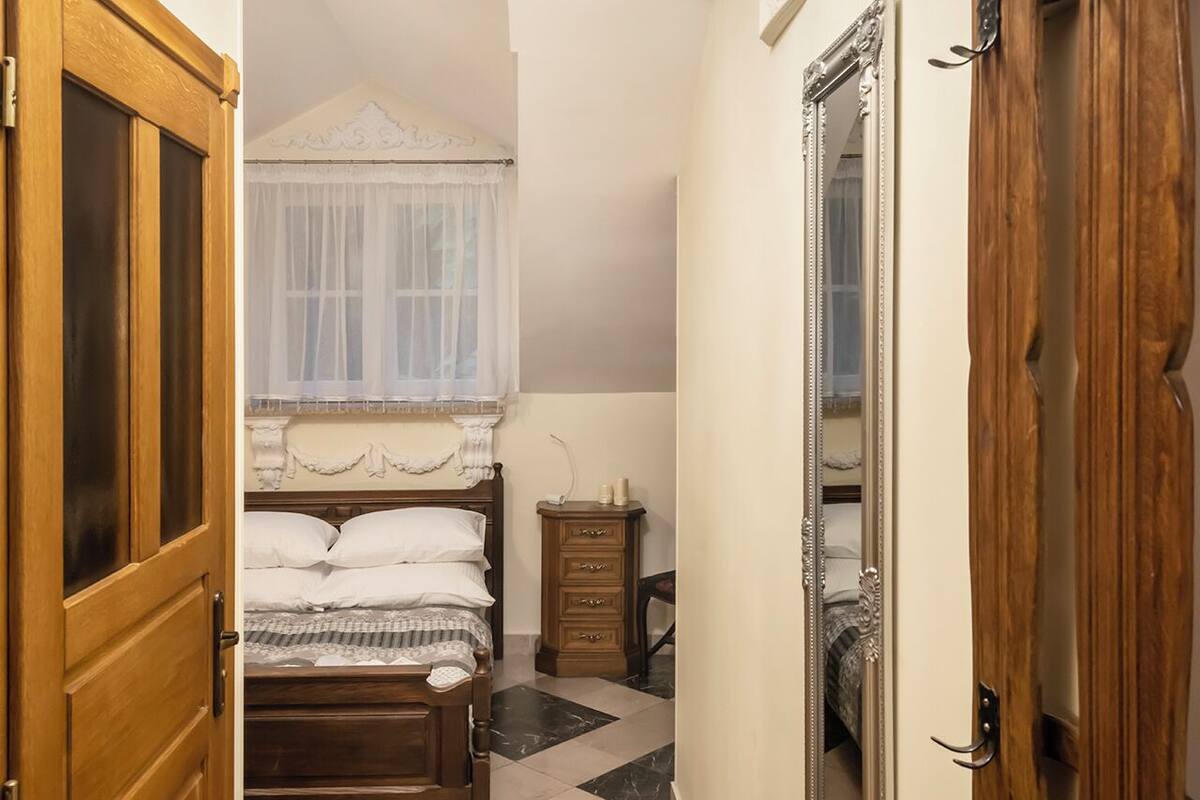 Une chambre à coucher avec un lit, une armoire en bois, un miroir et un lustre.