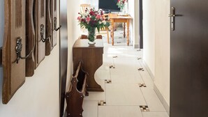 Ein Flur mit einem hölzernen Wandgarderobe, einem Holztisch mit Blumenvase, einem Fernseher und einer Tür mit Spiegel.
