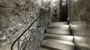 Eine Marmortreppe mit aufwendig gestalteten Metallgeländern und einem an der Wand befestigten Spiegel.