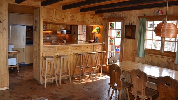 Un interior de madera con cocina, barra y zona de comedor.