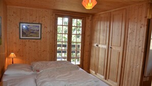 Una habitación con paneles de madera, una cama, un cuadro en la pared y una ventana.