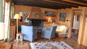 Una sala de estar acogedora con chimenea, paredes de madera, un sofá y una mesa de centro.