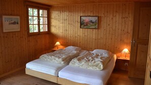Una habitación con paneles de madera, una cama doble, dos lámparas de noche y un cuadro en la pared.