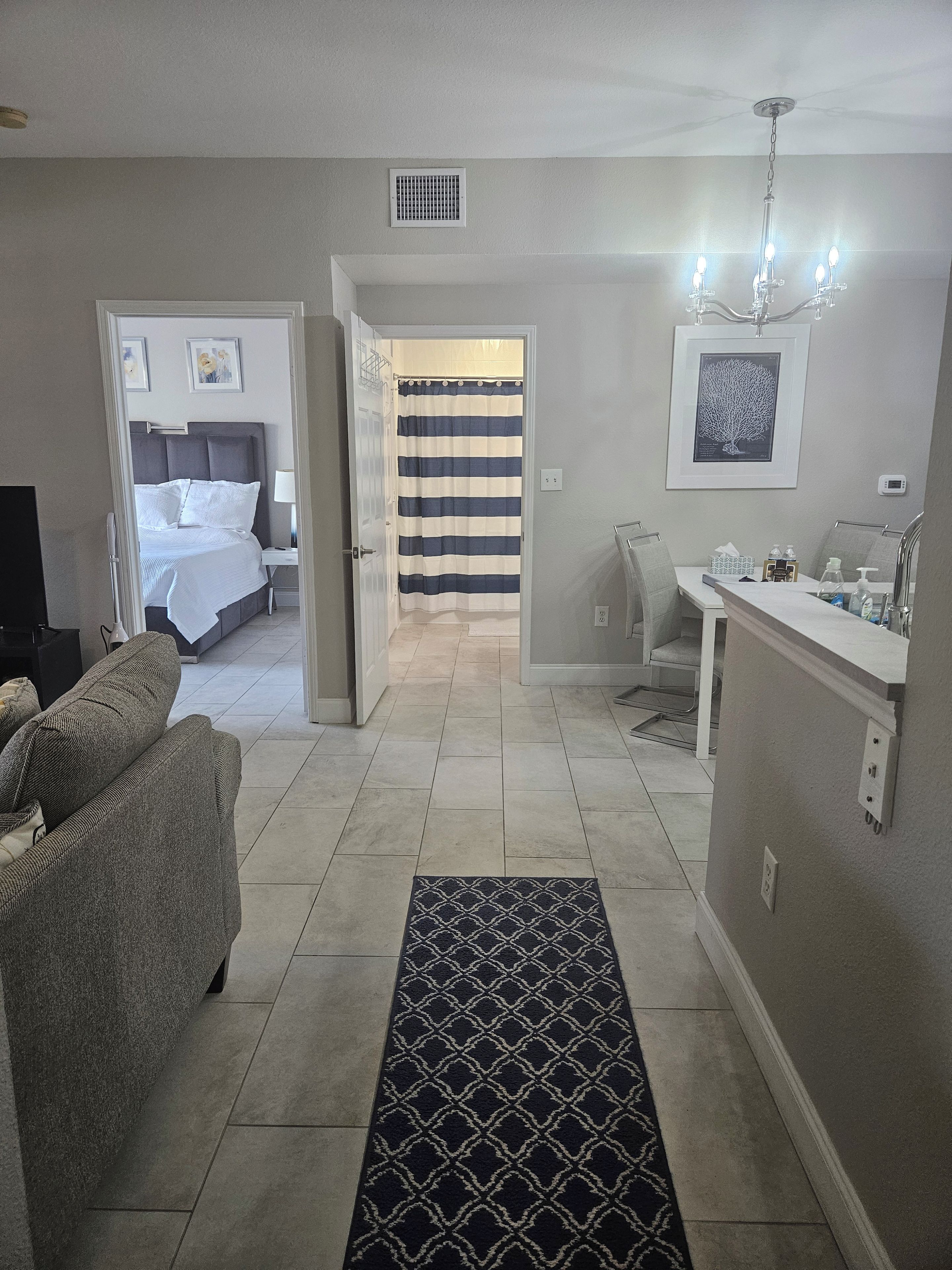 Ein Hotelzimmer mit Bett, einer Sitzecke mit Sofa, einem Badezimmer mit Dusche und einem Flur, der zu einem anderen Zimmer führt.