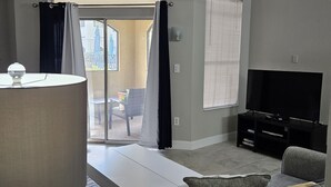 A living room with a ceiling fan, a TV, a sofa, and a coffee table. - Ground floor pool view retreat with free parking.  (Clearwater)