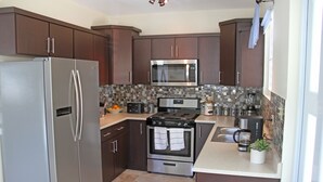 Una cocina moderna con electrodomésticos de acero inoxidable, armarios de madera oscura y un revoque de azulejos.