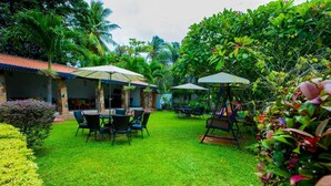 A lush garden with a dining area, outdoor seating, and a swing set. - Euro Star Hotel (Seeduwa - Katunayake)