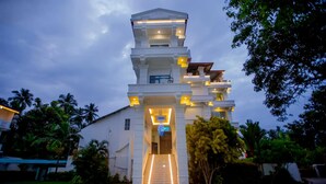 A multi-story building with a central staircase leading to the entrance, surrounded by lush greenery. - Euro Star Hotel (Seeduwa - Katunayake)
