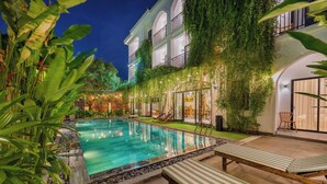 Uma área de piscina com espreguiçadeiras e um edifício com varandas.