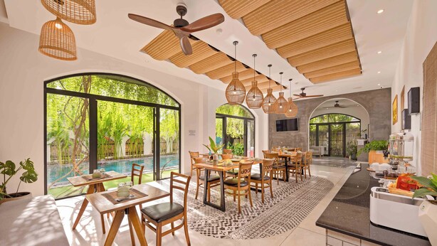 Uma sala de jantar espaçosa, com muita luz natural, vista para a piscina e uma área de cozinha moderna.