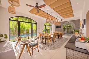 Un comedor amplio con luz natural, vistas a la piscina y una cocina moderna.