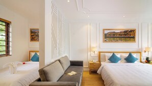 Quarto de hotel com duas camas, um sofá, um painel decorativo e obras de arte nas paredes.