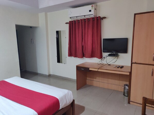 A hotel room with a bed, desk, television, and wardrobe. - Hotel Rahul (Jabalpur)