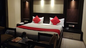 A hotel room with a large bed, two bedside tables, a desk with a chair, and a large mirror above the bed. - Hotel Rahul (Jabalpur)