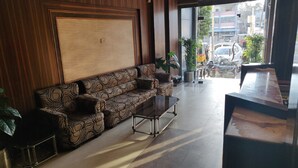 A modern lobby with a patterned sofa, a glass coffee table, and potted plants. - Hotel Rahul (Jabalpur)