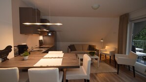 Cocina moderna con comedor, muebles blancos y vistas al exterior.