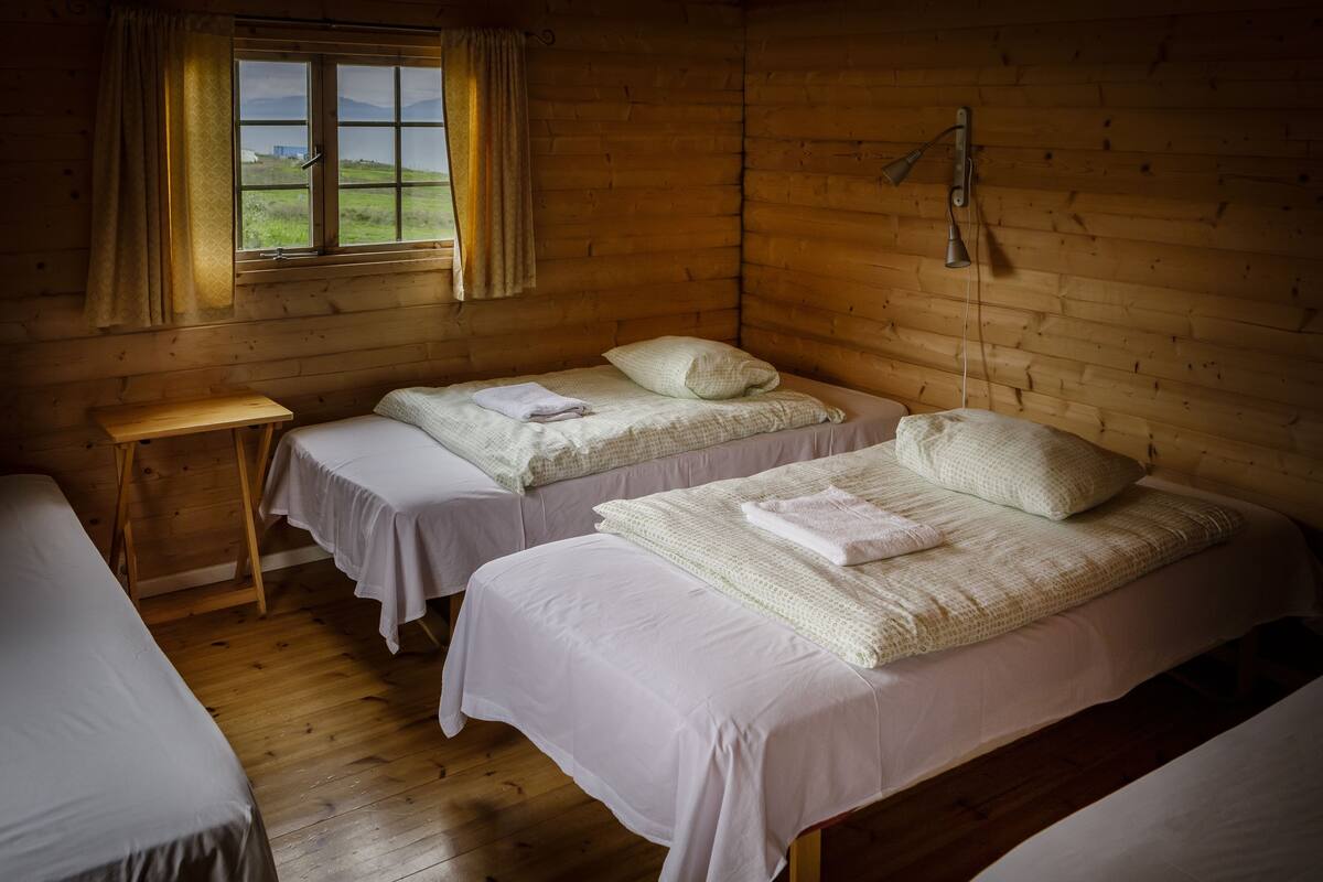 A cabin with two single beds, a small table, and a window with curtains.