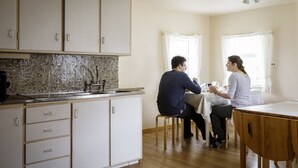Una cocina con armarios blancos, salpicadero de azulejos y una mesa de comedor de madera.
