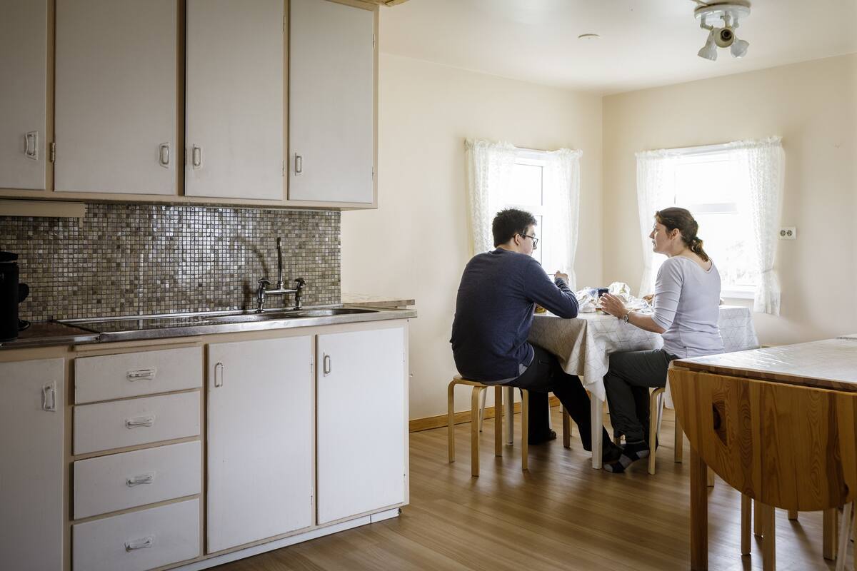 A kitchen with white cabinets, a tiled backsplash, and a wooden dining table.