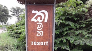 A wooden sign for a resort with a thatched roof, surrounded by lush greenery. - Kamatha Resort (Polonnaruwa)