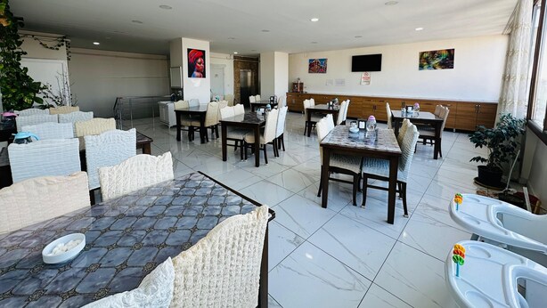 A spacious dining area with multiple tables and chairs, a tiled floor, and a ceiling with recessed lighting. -  Van Toprak Hotel (Van)