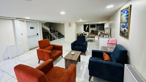 A hotel lobby with seating, a staircase, a kitchen area, and a framed picture on the wall. -  Van Toprak Hotel (Van)