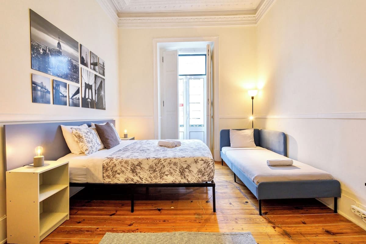Une chambre à coucher avec un lit, une table de chevet et un petit banc.